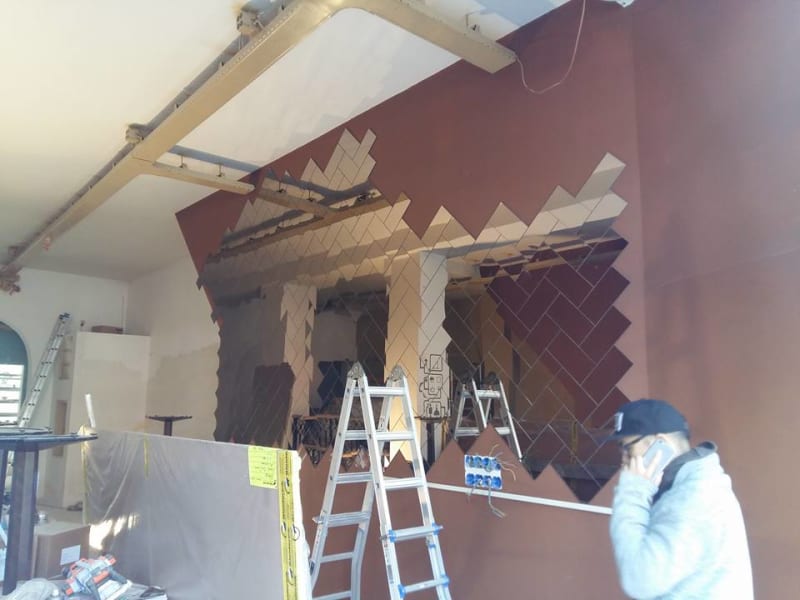 Rectangular-cut herringbone pattern mirror wall installation showing more progress